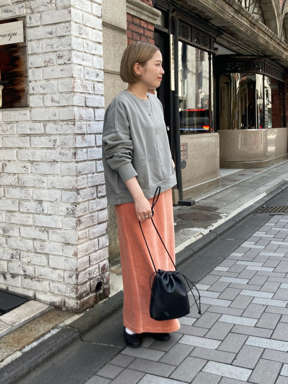 グレー系のスウェット、ピンク系のスカート、ブラック系のショルダーバッグを着用したレディースの秋コーディネートの3枚目の写真