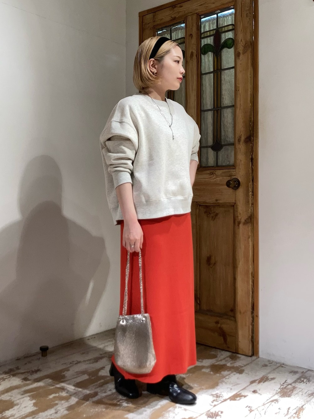 オレンジ系のスカート、ゴールド系のショルダーバッグ、ベージュ系のスウェットを着用したレディースの秋コーディネートの2枚目の写真