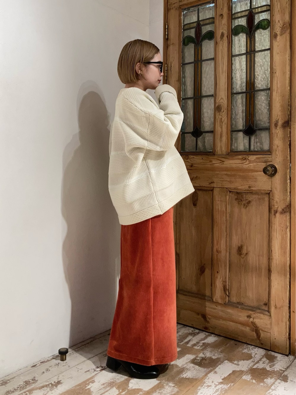 ブラック系のブーツ、ゴールド系のショルダーバッグ、オレンジ系のスカートを着用したレディースの冬コーディネートの2枚目の写真