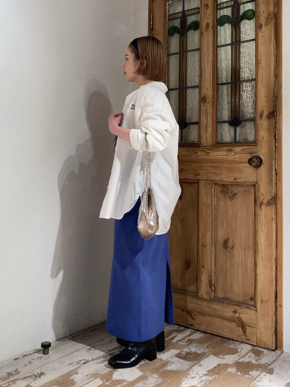 ブラック系のブーツ、ゴールド系のショルダーバッグ、ブルー系のスカートを着用したレディースの春コーディネートの4枚目の写真