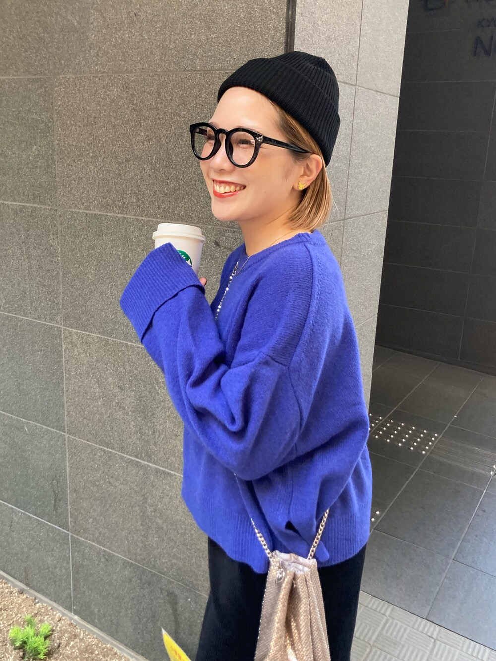 ブルー系のニット/セーター、ブラック系のスカート、ゴールド系のショルダーバッグを着用したレディースの秋コーディネートの4枚目の写真