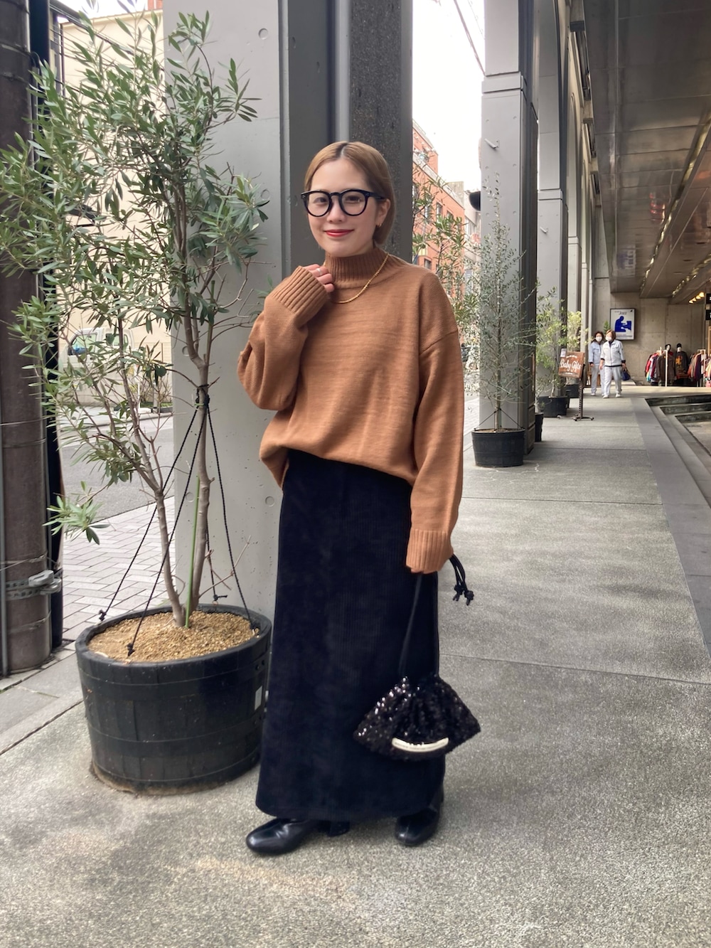 ブラック系のスカート、ベージュ系のニット/セーター、ブラック系のショルダーバッグを着用したレディースの冬コーディネートの2枚目の写真