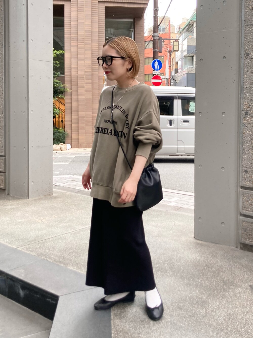 ブラック系のスカート、ベージュ系のスウェット、ブラック系のショルダーバッグを着用したレディースの秋コーディネートの3枚目の写真