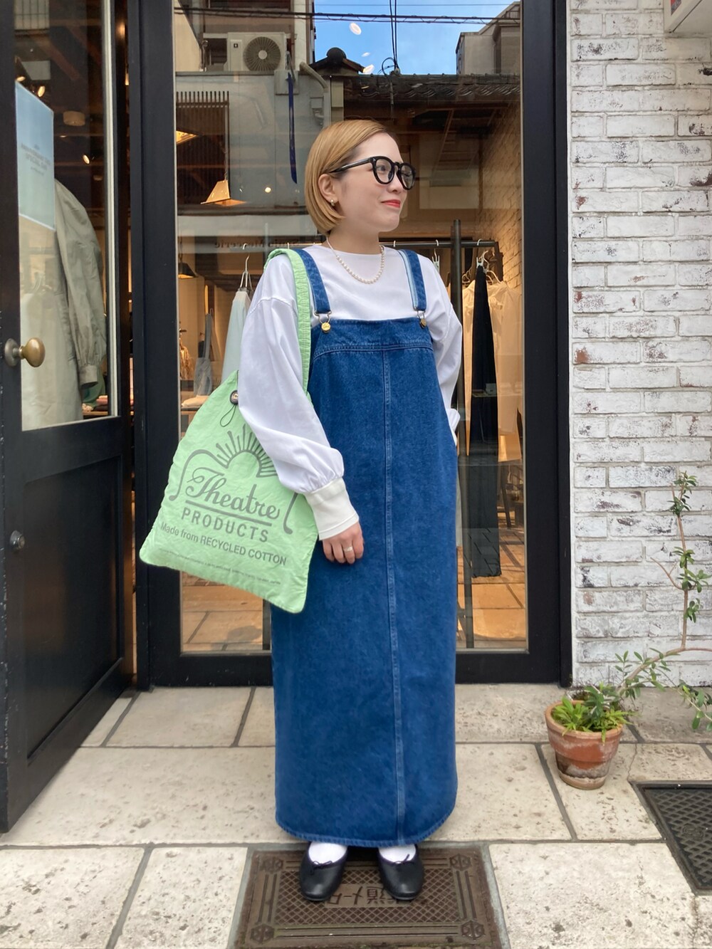 ブルー系のジャンパースカート、グリーン系のバッグ、ホワイト系のシャツ/ブラウスを着用したレディースの冬コーディネートの2枚目の写真