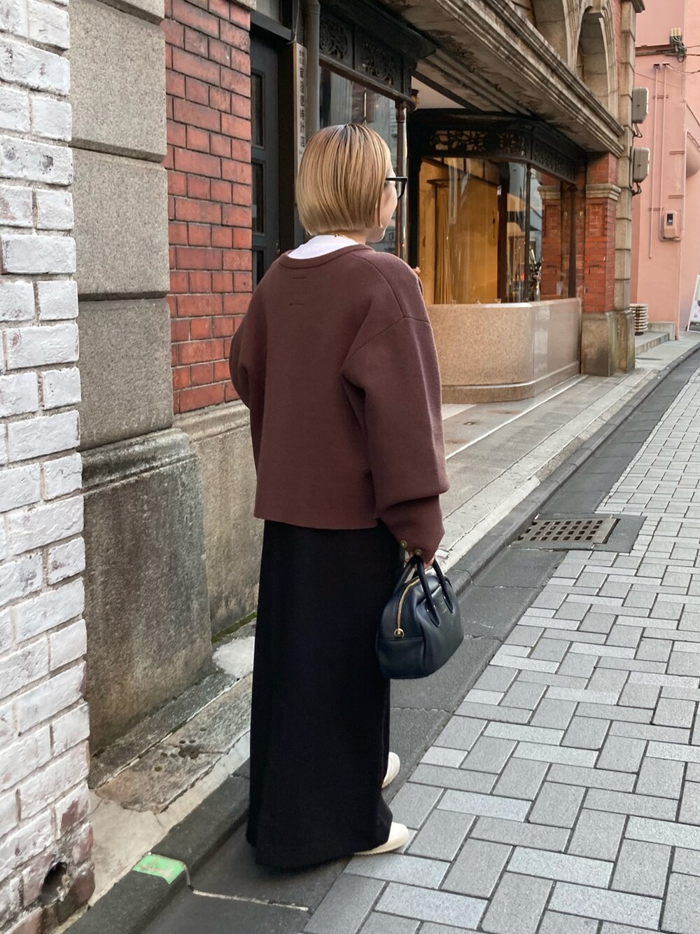 ブラック系のショルダーバッグ、ブラウン系のカーディガン/ボレロ、ブラック系のワンピースを着用したレディースの秋コーディネートの4枚目の写真