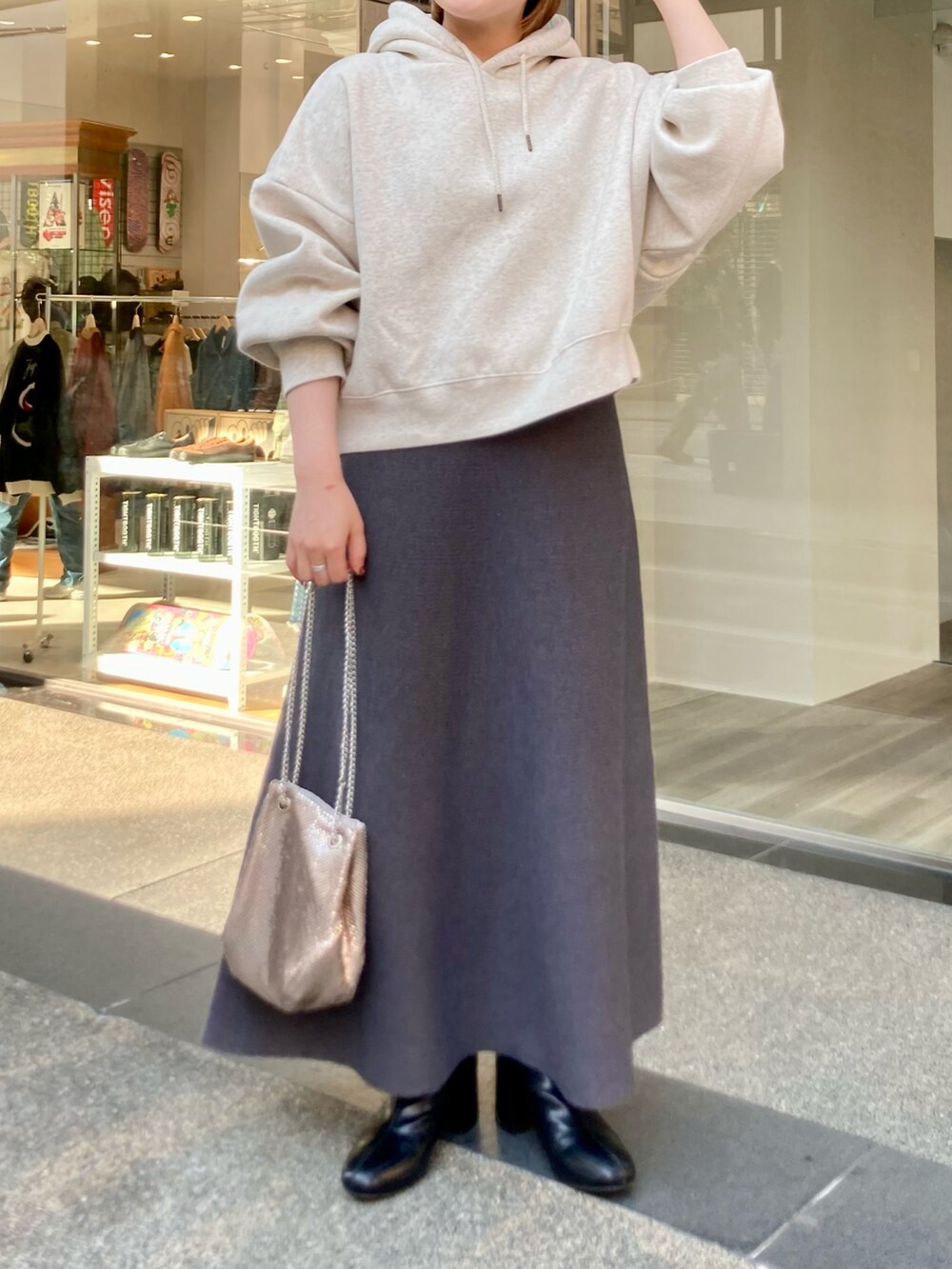 ブラック系のブーツ、グレー系のスカート、ゴールド系のショルダーバッグを着用したレディースの秋コーディネートの4枚目の写真