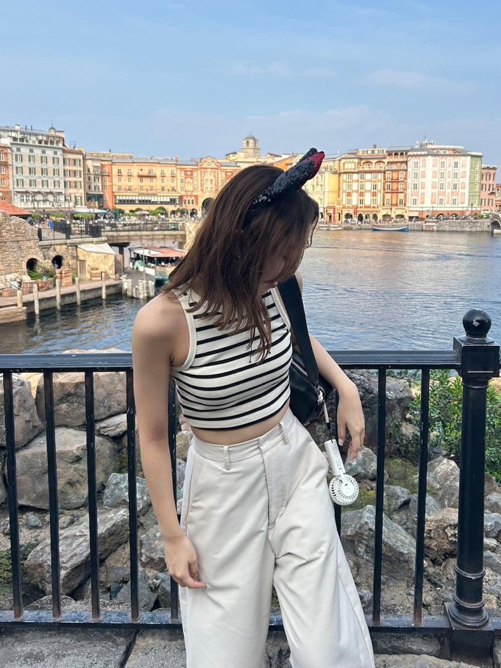 ホワイト系のスラックス、ホワイト系のタンクトップ、ブラック系のショルダーバッグを着用したレディースの夏コーディネートの2枚目の写真