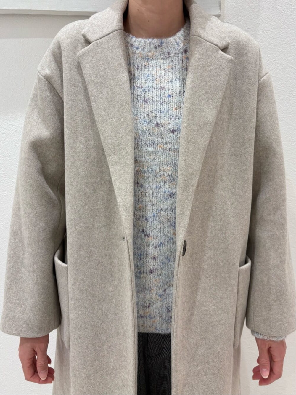 ブラック系のボストンバッグ、ベージュ系のチェスターコート、ホワイト系のニット/セーターを着用したレディースの冬コーディネートの2枚目の写真