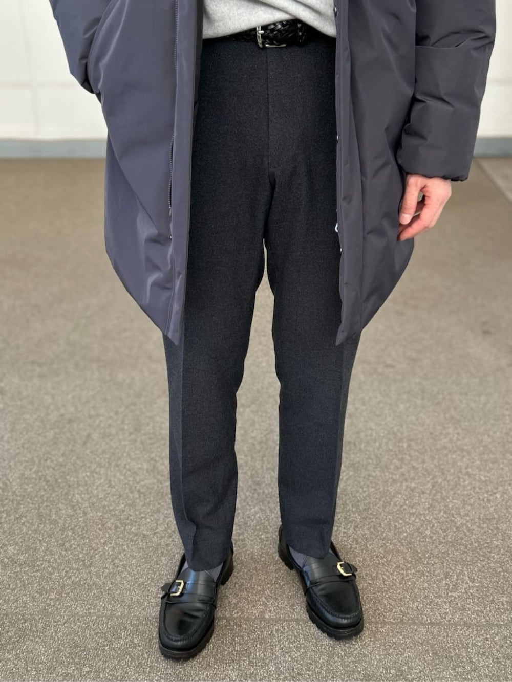 グレー系のその他アウター、グレー系のニット/セーター、グレー系のスラックスを着用したメンズの冬コーディネートの3枚目の写真