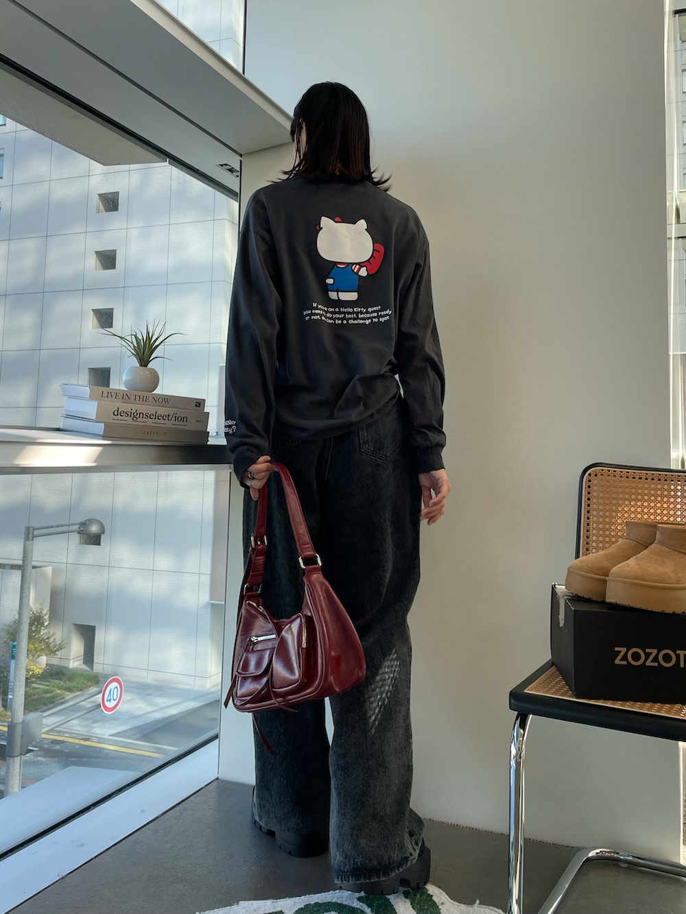 ブラウン系のショルダーバッグ、ブラック系のブーツ、ブラック系のデニムパンツを着用したレディースの秋コーディネートの2枚目の写真