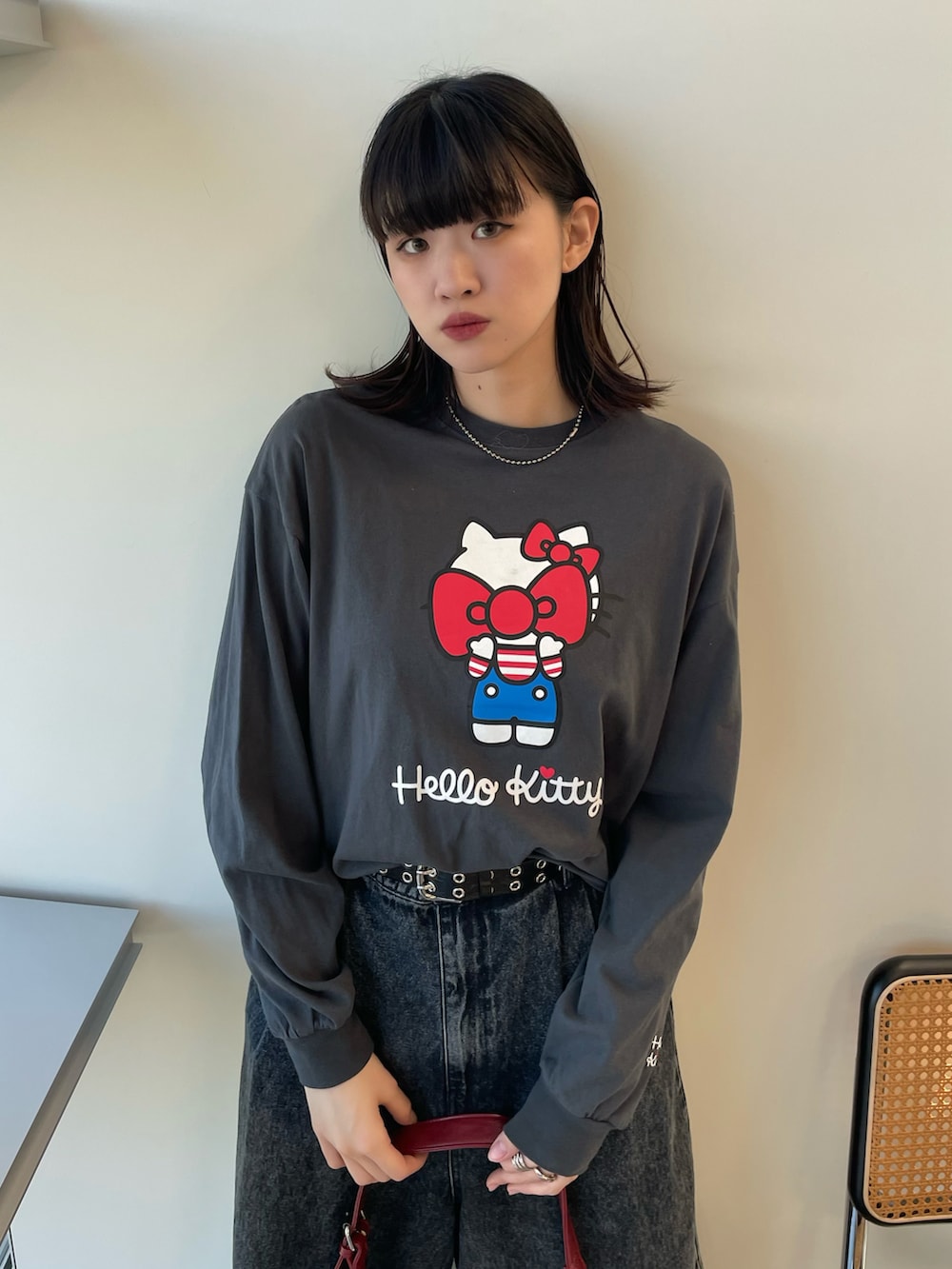 ブラウン系のショルダーバッグ、ブラック系のブーツ、ブラック系のデニムパンツを着用したレディースの秋コーディネートの3枚目の写真