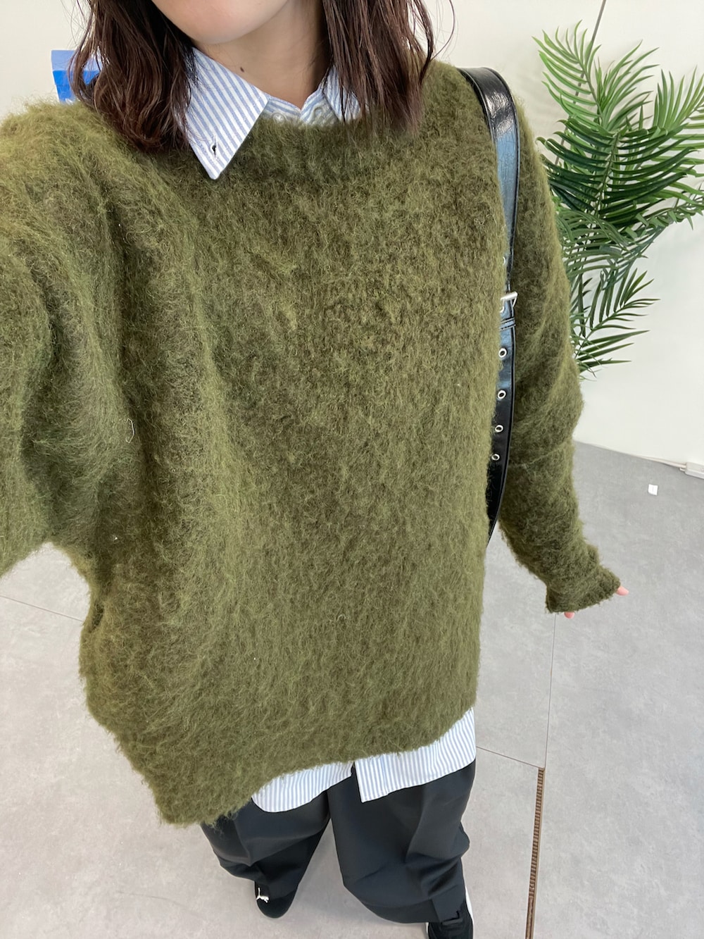 グリーン系のニット/セーター、ブラック系のショルダーバッグ、ブラック系のスラックスを着用したレディースの冬コーディネートの4枚目の写真