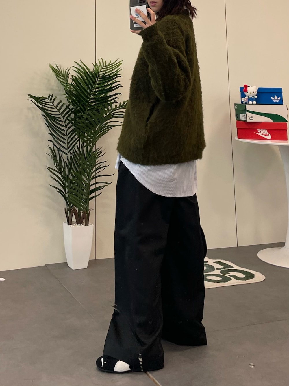 グリーン系のニット/セーター、ブラック系のショルダーバッグ、ブラック系のスラックスを着用したレディースの冬コーディネートの2枚目の写真