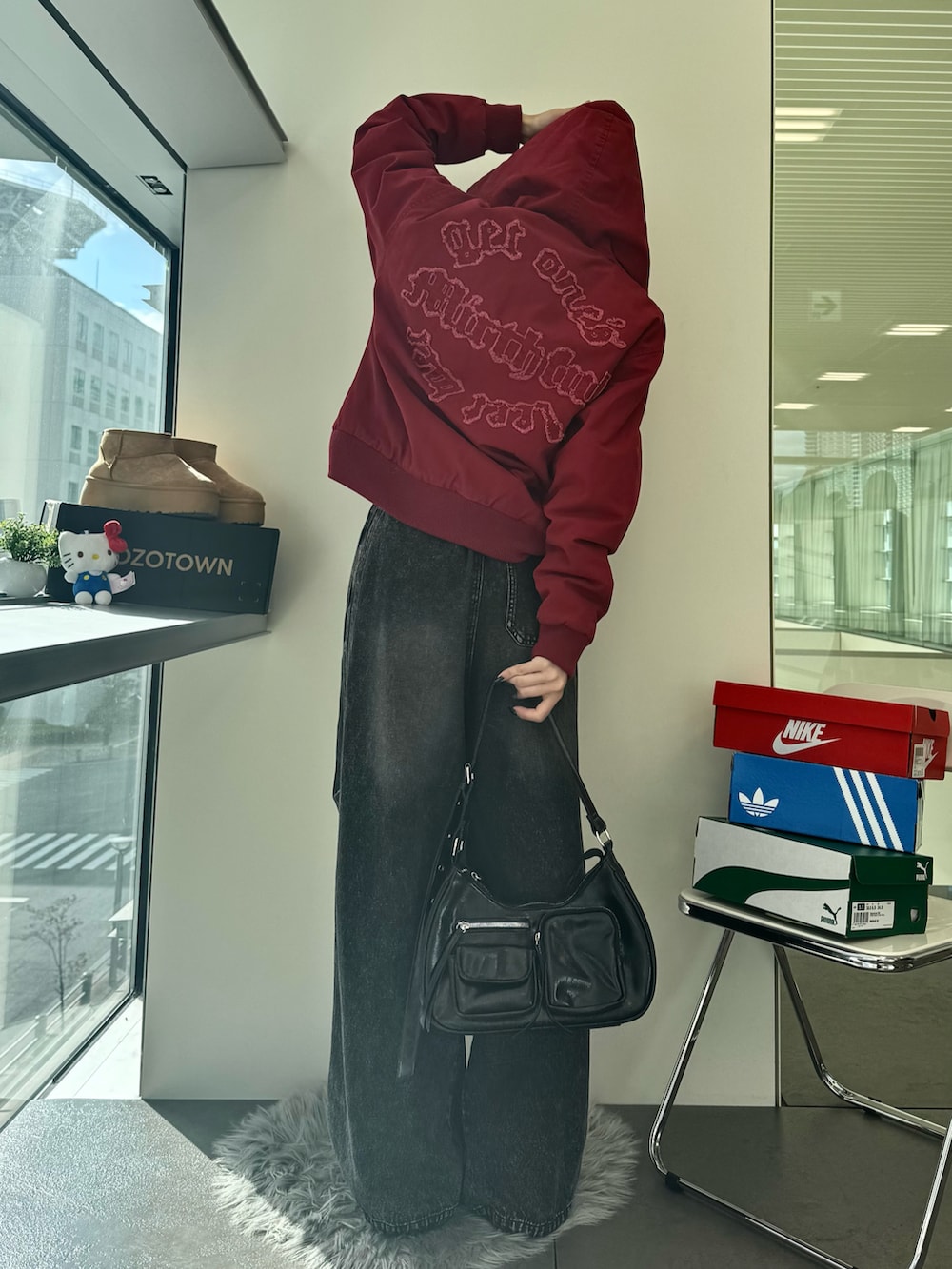 ブラック系のデニムパンツ、ブラウン系のブーツ、ブラック系のショルダーバッグを着用したレディースの秋コーディネートの3枚目の写真