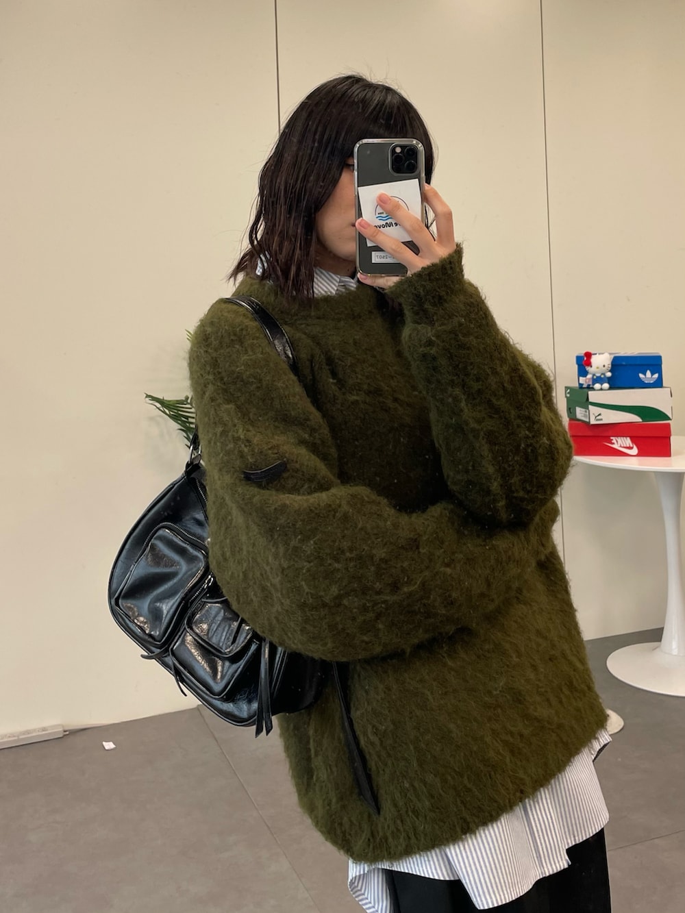 グリーン系のニット/セーター、ブラック系のショルダーバッグ、ブラック系のスラックスを着用したレディースの冬コーディネートの3枚目の写真