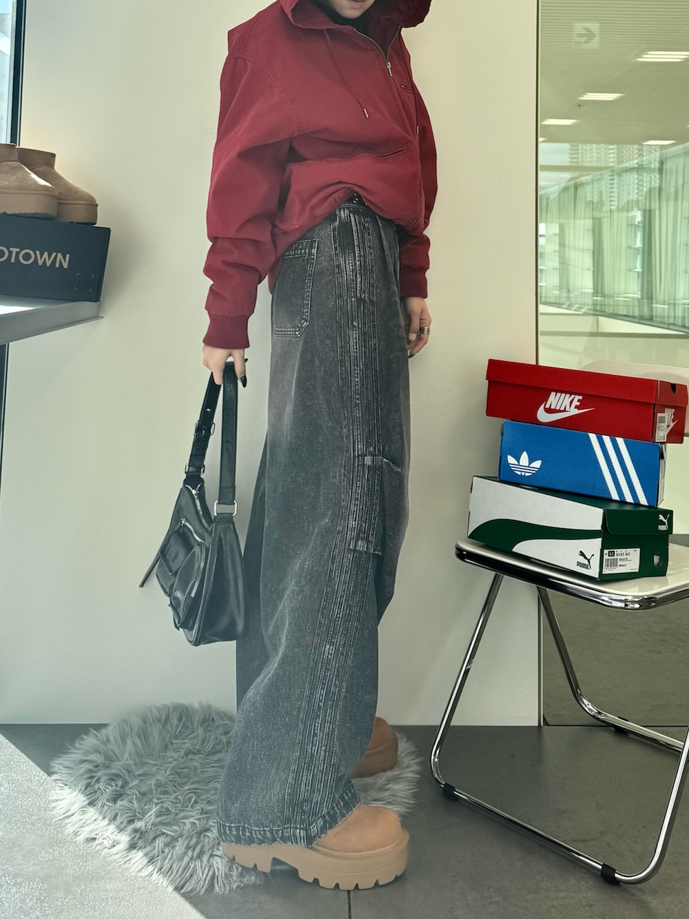 ブラック系のデニムパンツ、ブラウン系のブーツ、ブラック系のショルダーバッグを着用したレディースの秋コーディネートの2枚目の写真