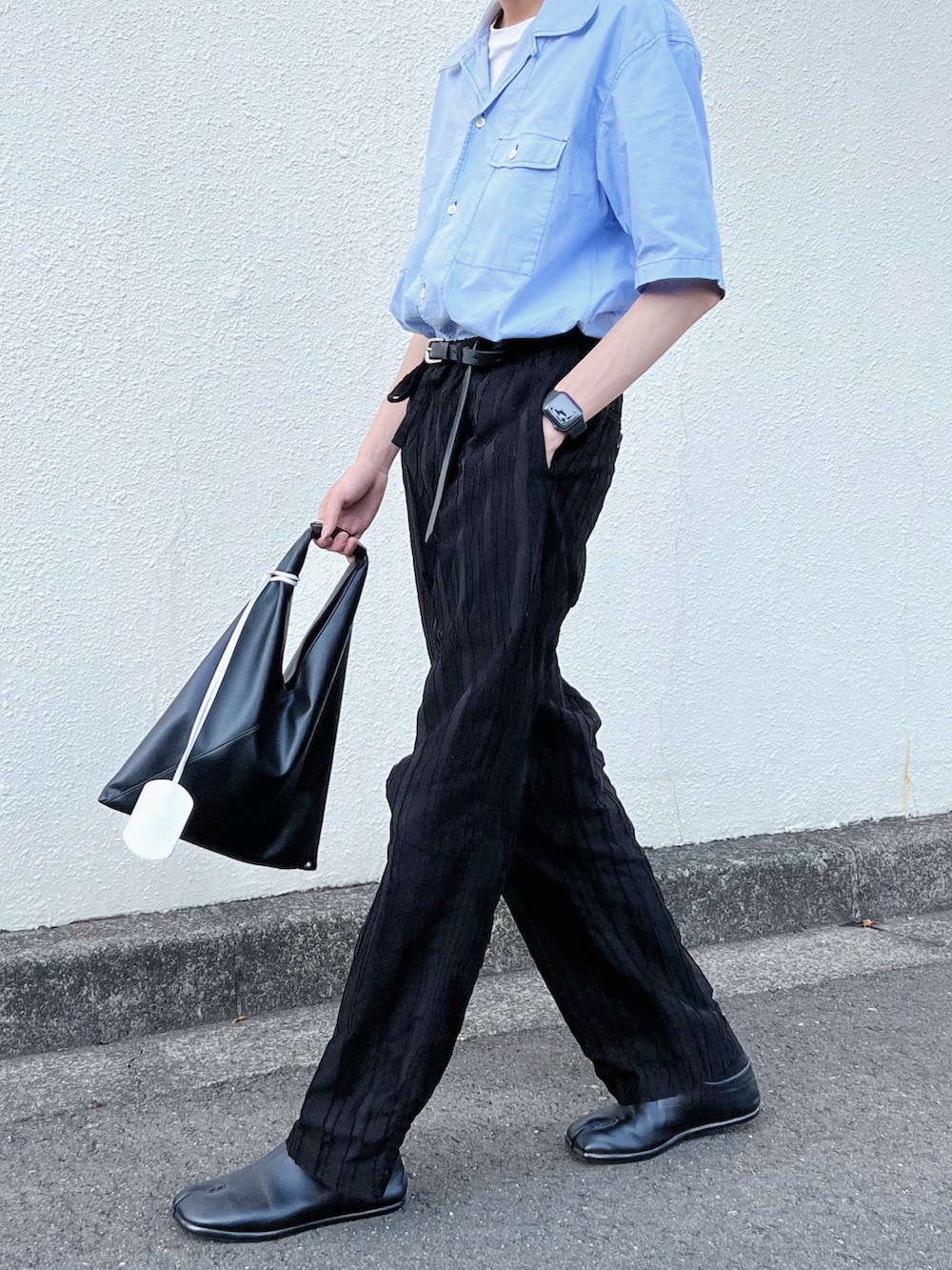 ブラック系のパンツ、ブラック系のトートバッグ、ブルー系のシャツ/ブラウスを着用したメンズの夏コーディネートの2枚目の写真