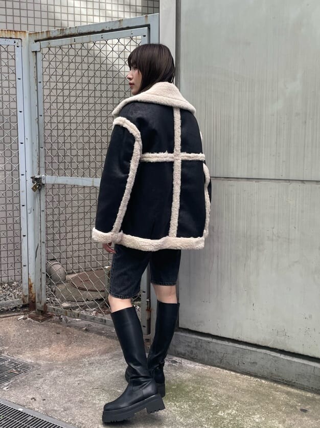 ブラック系のブーツ、ブルー系のニット/セーター、ブラック系のムートンコートを着用したレディースの秋コーディネートの4枚目の写真