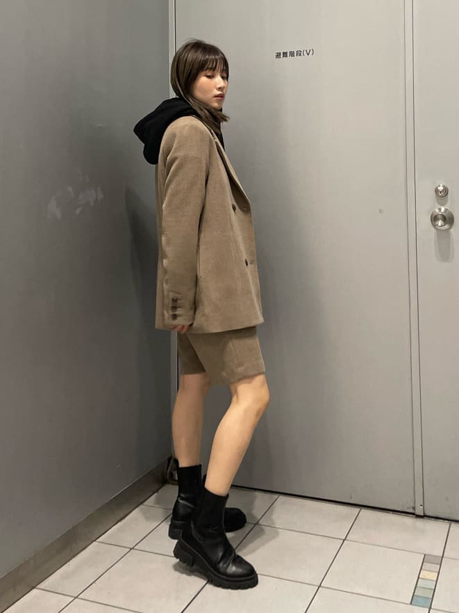 ブラック系のブーツ、ブラウン系のテーラードジャケット、ブラウン系のスラックスを着用したレディースの秋コーディネートの2枚目の写真