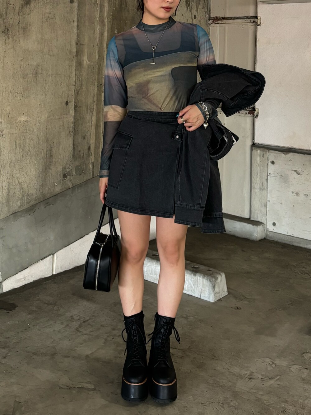 ブラック系のデニムジャケット、ブラック系のスカート、ブラック系のブーツを着用したレディースの夏コーディネートの4枚目の写真