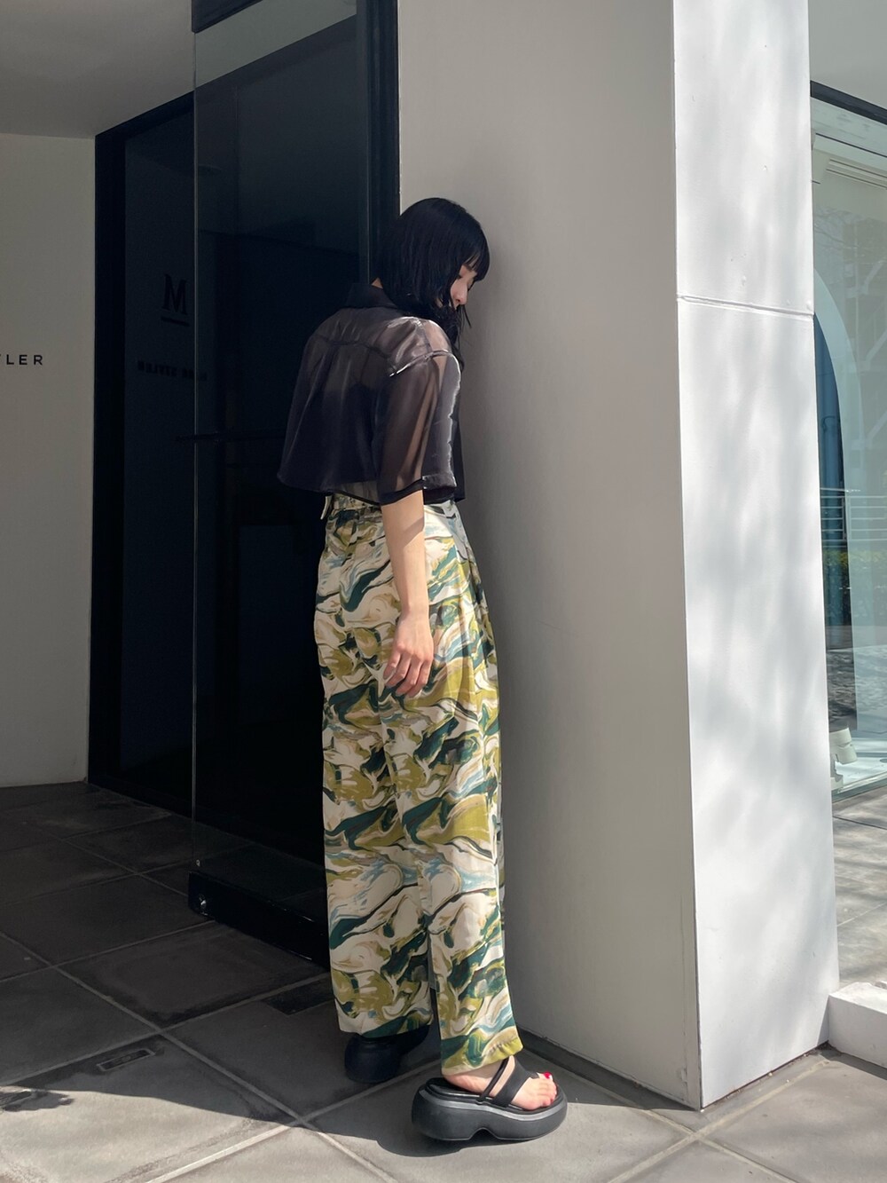 ブラック系のシャツ/ブラウス、グリーン系のスラックス、ブラック系のサンダルを着用したレディースの春コーディネートの5枚目の写真