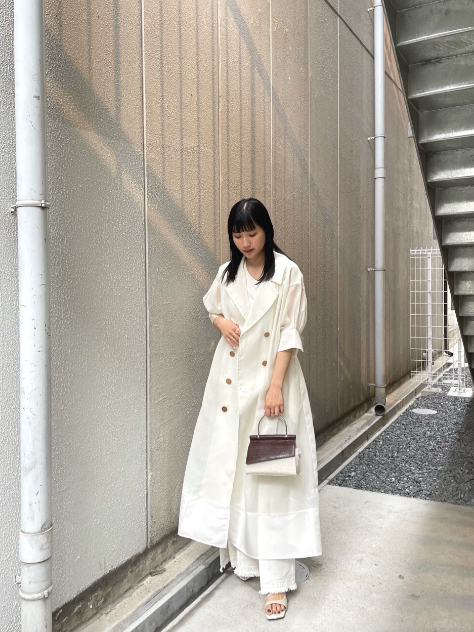 ホワイト系のニット/セーター、ホワイト系のサンダル、ブラウン系のハンドバッグを着用したレディースの春コーディネートの2枚目の写真