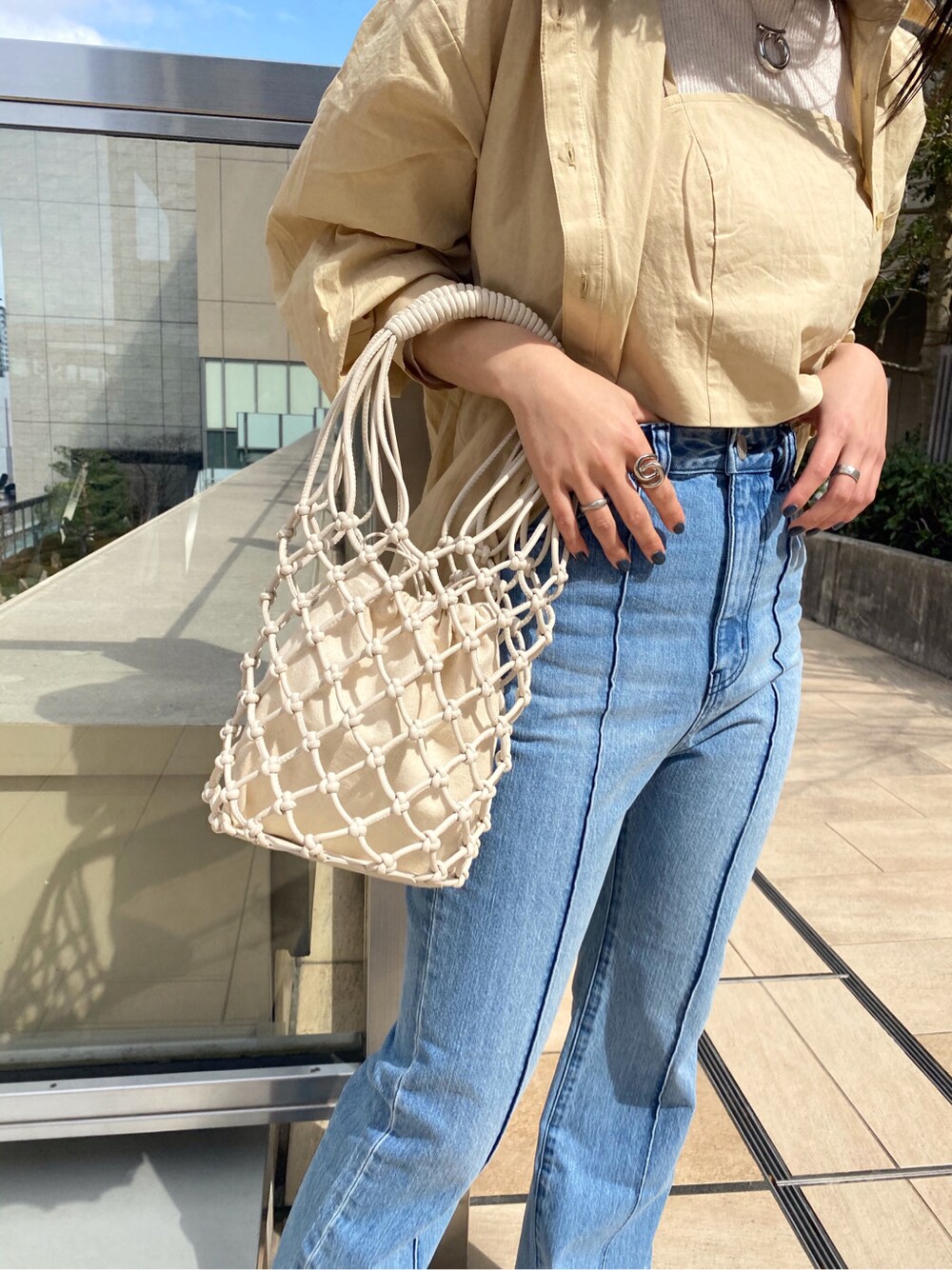 ホワイト系のニット/セーター、イエロー系のシャツ/ブラウス、ホワイト系のハンドバッグを着用したレディースの春コーディネートの2枚目の写真