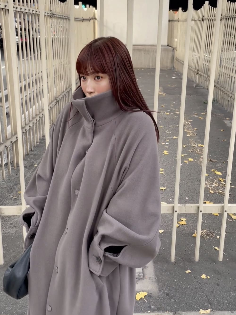 ブラウン系のステンカラーコートを着用したレディースの冬コーディネートの3枚目の写真