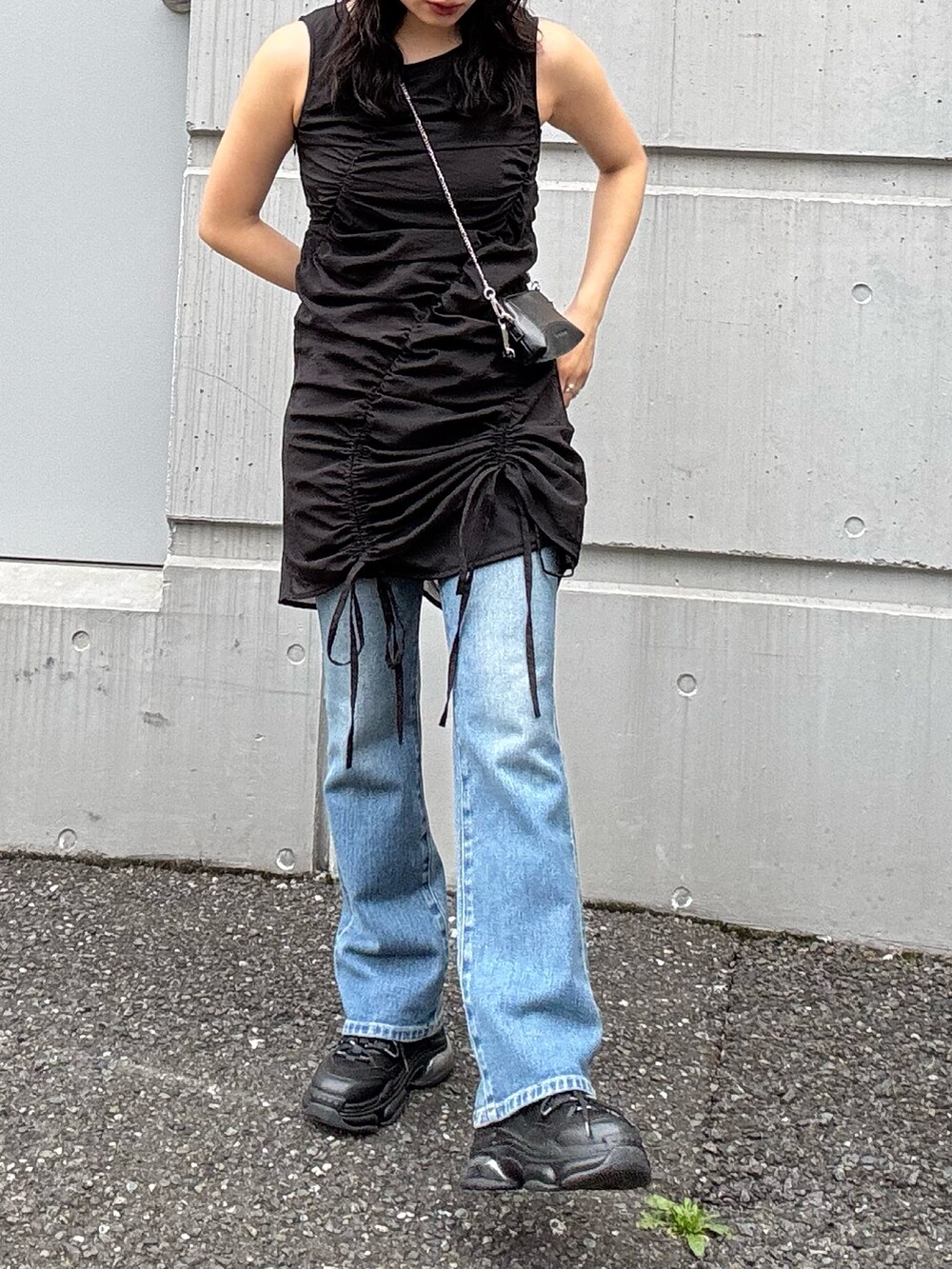 ブラック系のワンピース、ブルー系のデニムパンツ、ブラック系のスニーカーを着用したレディースの春コーディネートの2枚目の写真