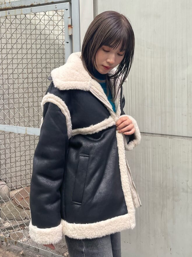 ブラック系のブーツ、ブルー系のニット/セーター、ブラック系のムートンコートを着用したレディースの秋コーディネートの6枚目の写真