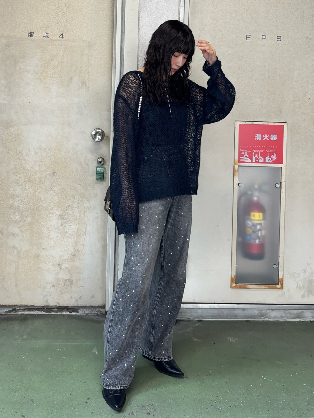 ブラック系のデニムパンツを着用したレディースの秋コーディネートの2枚目の写真