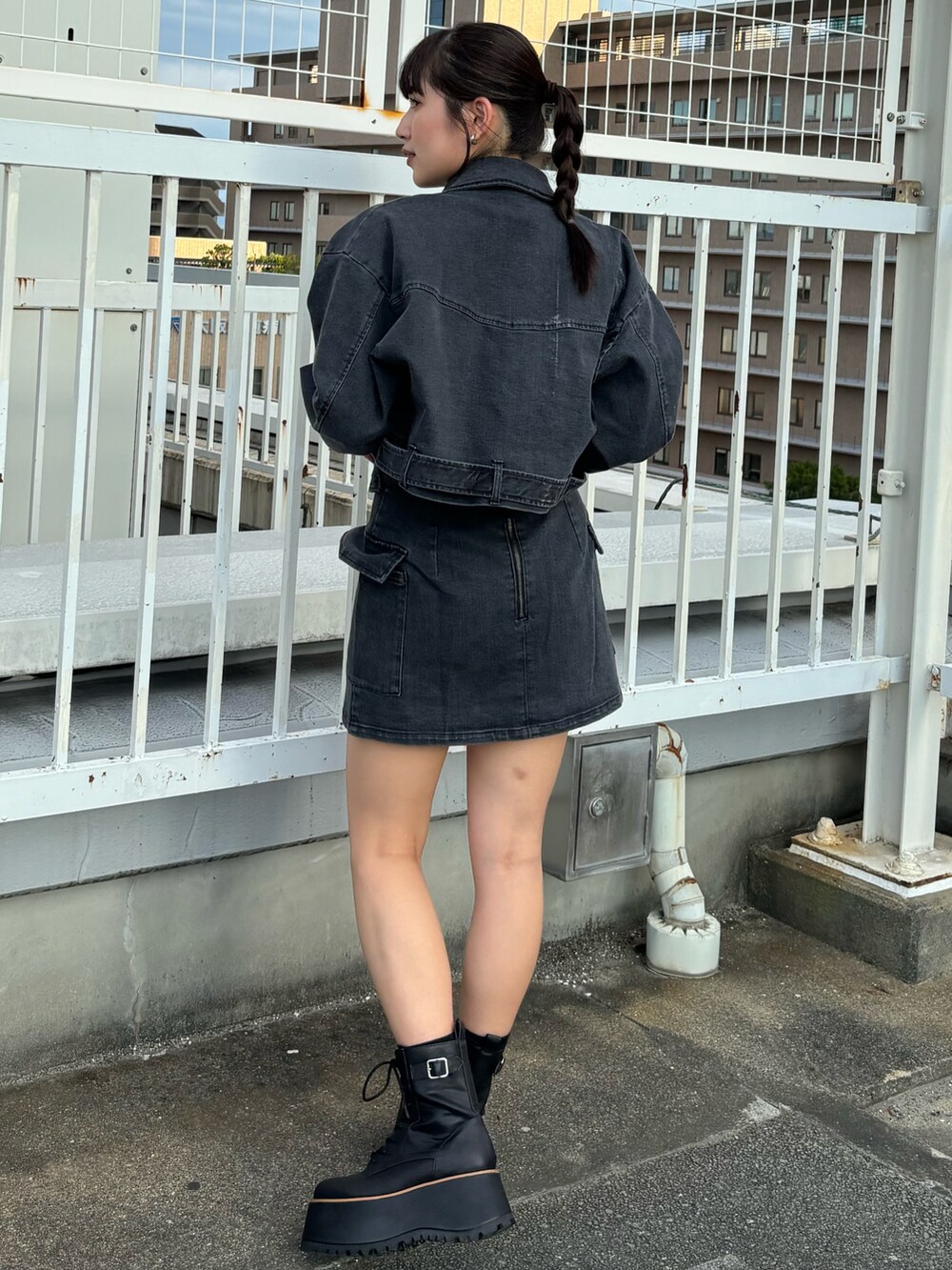 ブラック系のデニムジャケット、ブラック系のスカート、ブラック系のブーツを着用したレディースの夏コーディネートの3枚目の写真