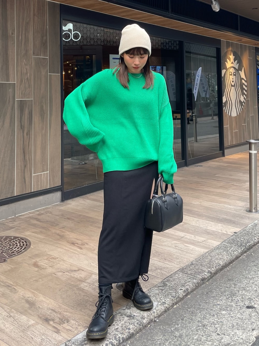 グリーン系のニット/セーター、ブラック系のスカートを着用したレディースの冬コーディネートの2枚目の写真
