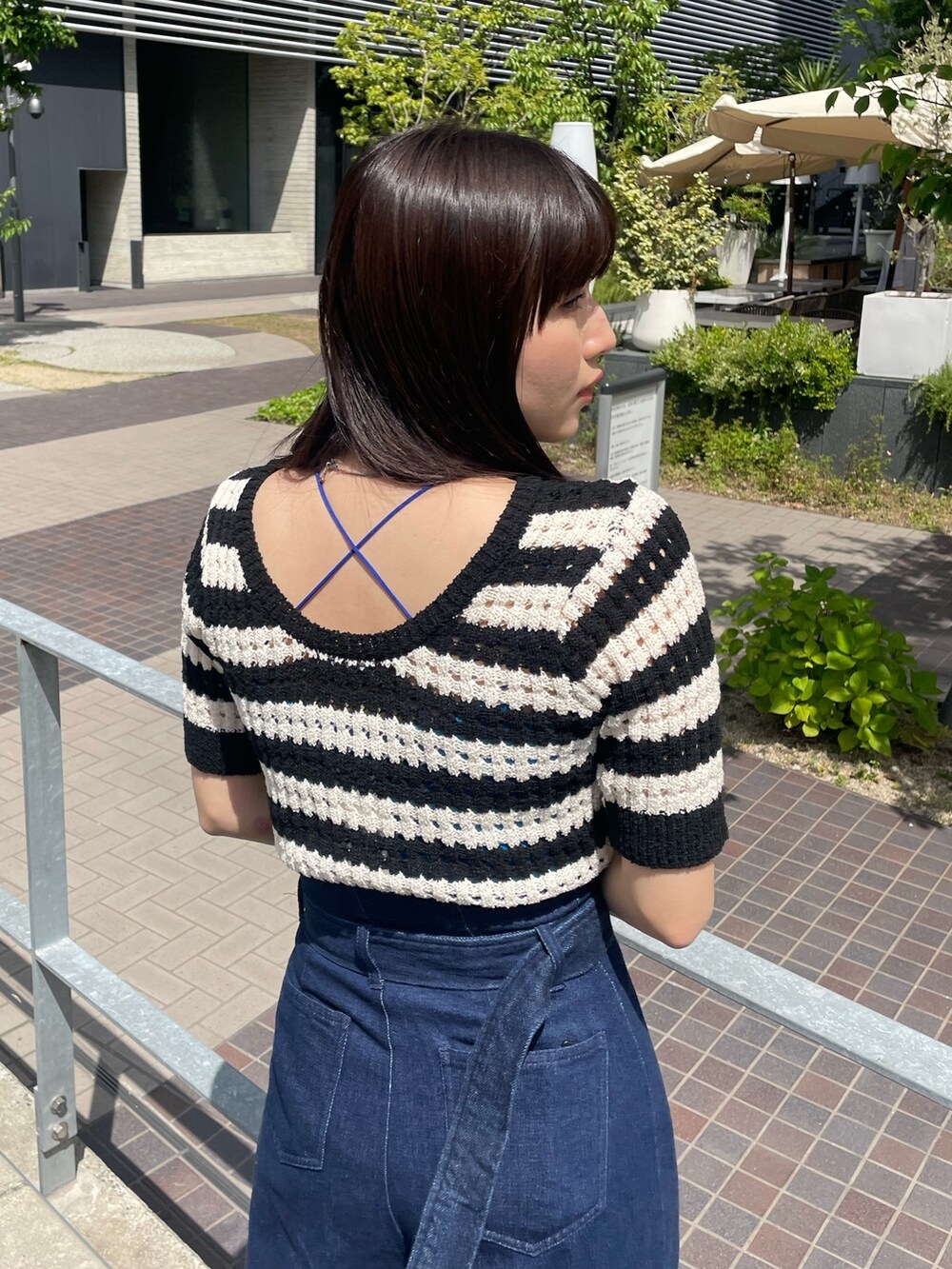 ブルー系のデニムパンツ、ブルー系のTシャツ/カットソー、ブラック系のニット/セーターを着用したレディースの春コーディネートの3枚目の写真