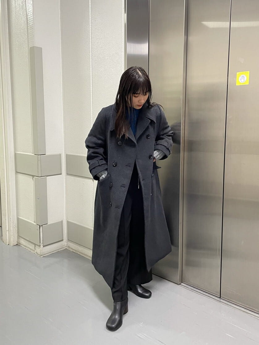 ブルー系のハンドバッグ、ブルー系のニット/セーター、ブラック系のチェスターコートを着用したレディースの秋コーディネートの2枚目の写真