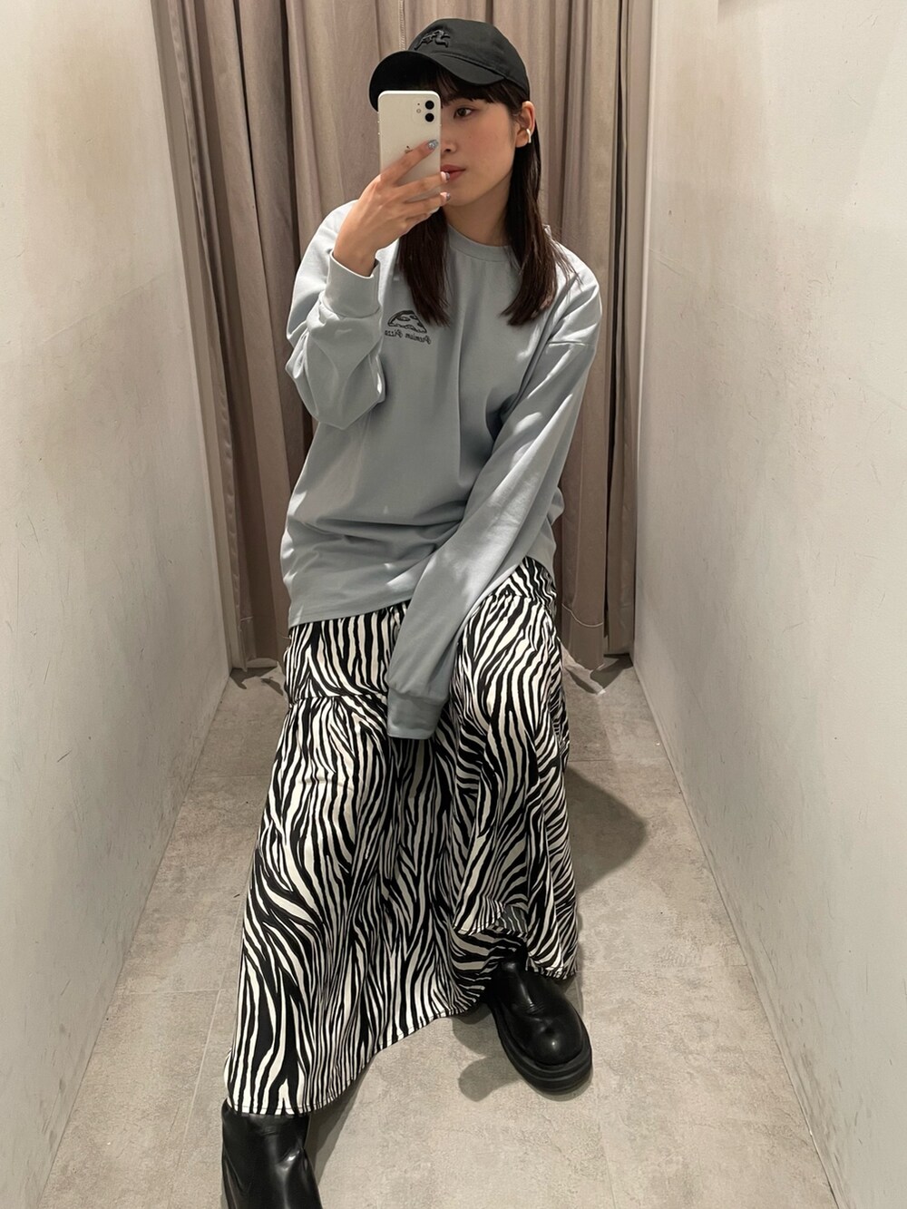 ホワイト系のスカート、ブルー系のTシャツ/カットソー、ブラック系のキャップを着用したレディースの冬コーディネートの2枚目の写真