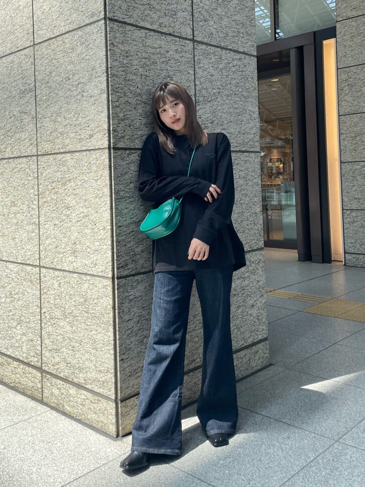 グリーン系のハンドバッグ、ブラック系のブーツ、ブラック系のTシャツ/カットソーを着用したレディースの夏コーディネートの3枚目の写真