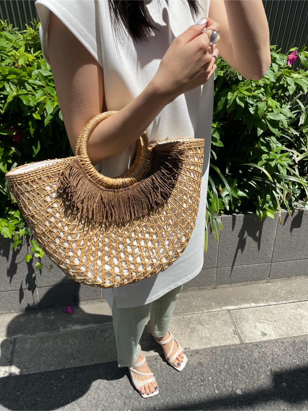 ホワイト系のワンピース、ホワイト系のサンダル、ベージュ系のかごバッグを着用したレディースの春コーディネートの3枚目の写真