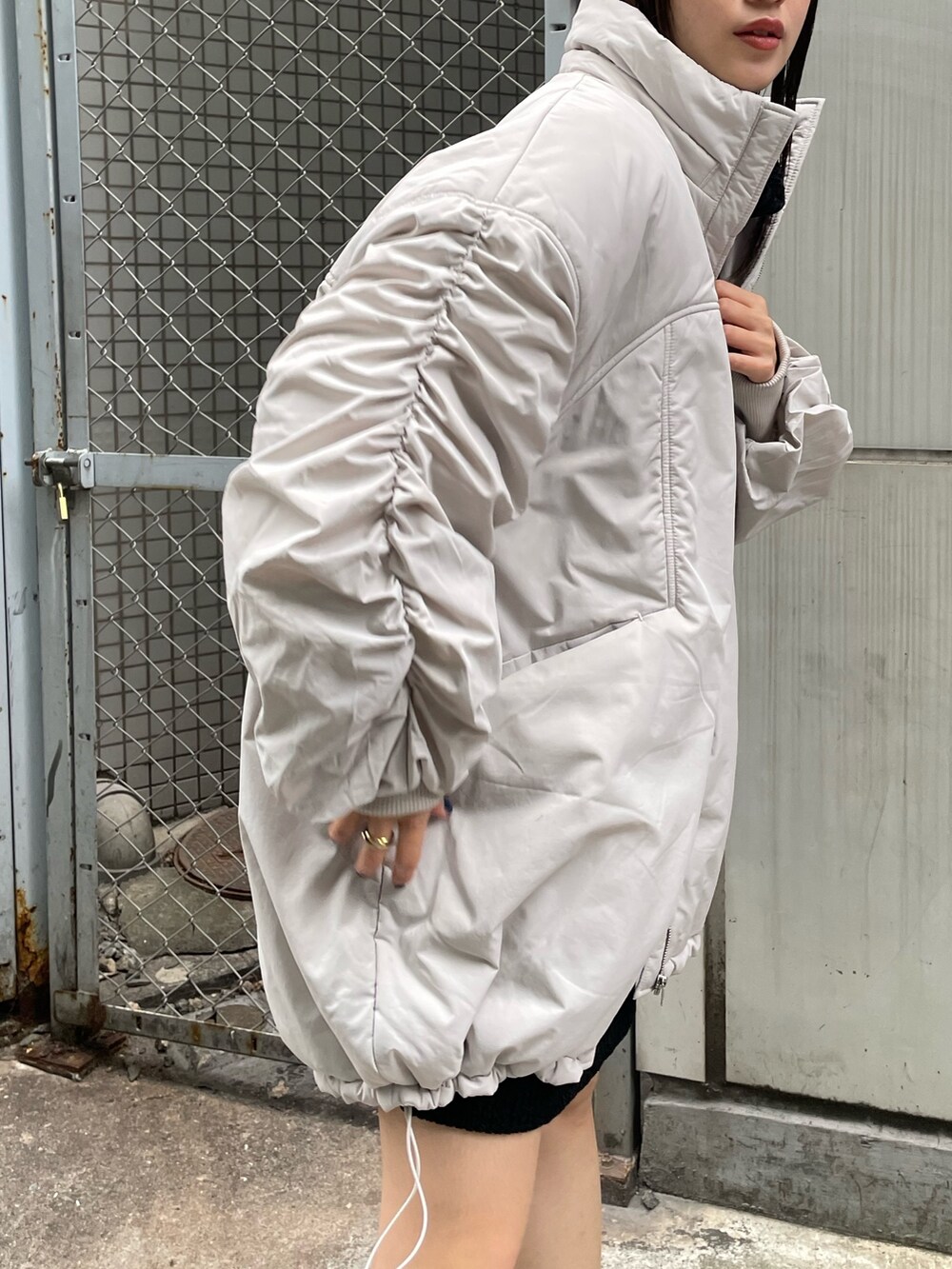 ホワイト系のブルゾン、ブラック系のワンピース、ブラック系のブーツを着用したレディースの冬コーディネートの5枚目の写真