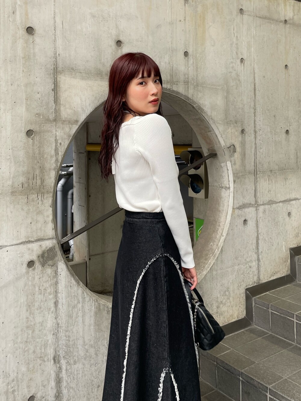 ホワイト系のニット/セーター、ブラック系のデニムスカートを着用したレディースの冬コーディネートの5枚目の写真
