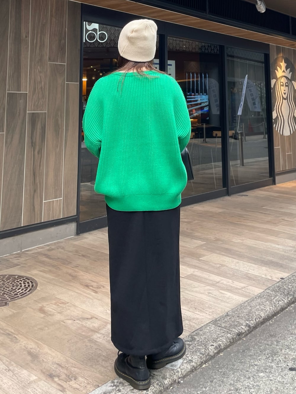 グリーン系のニット/セーター、ブラック系のスカートを着用したレディースの冬コーディネートの6枚目の写真