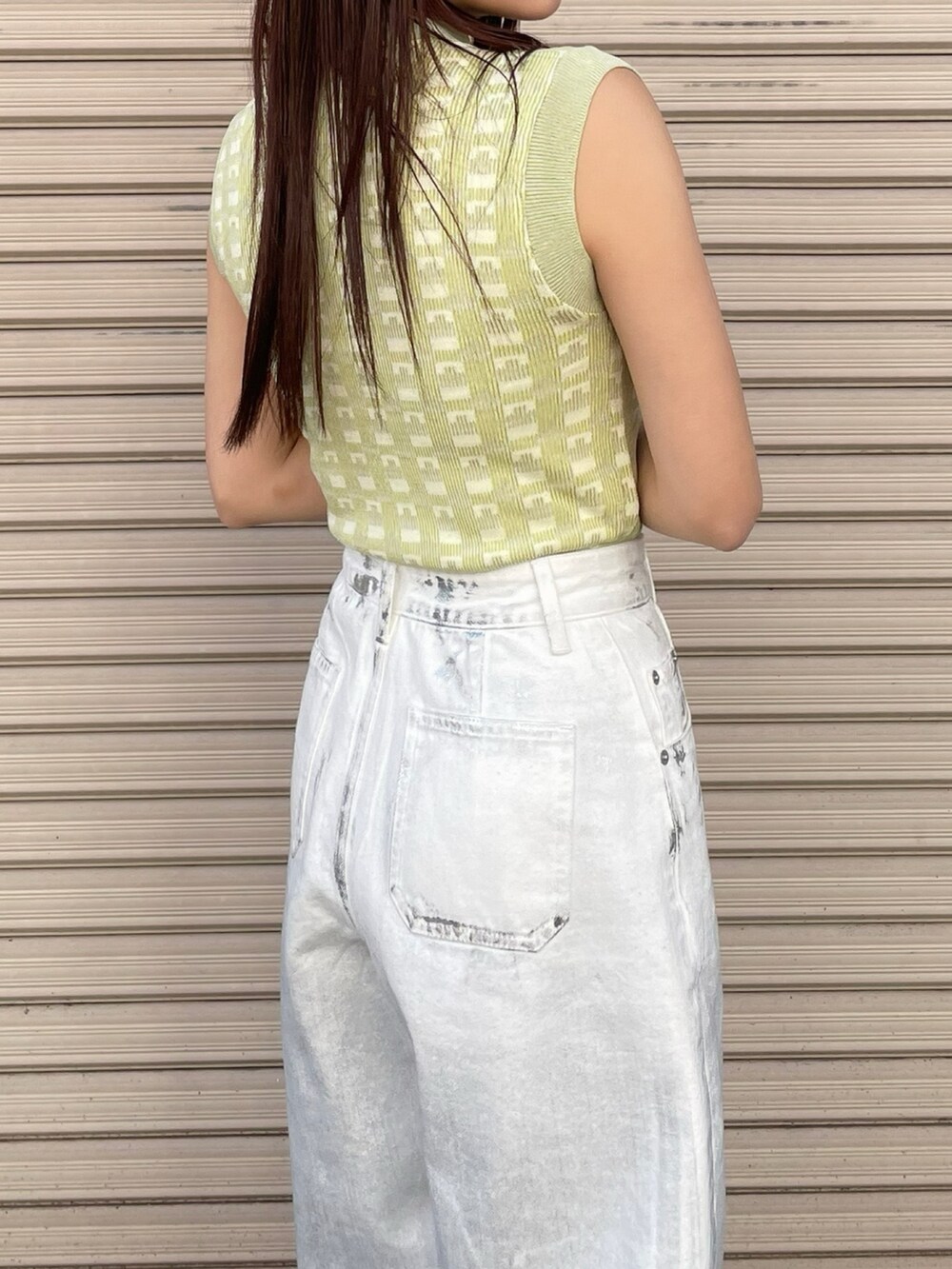 グリーン系のニット/セーター、ホワイト系のデニムパンツを着用したレディースの春コーディネートの2枚目の写真