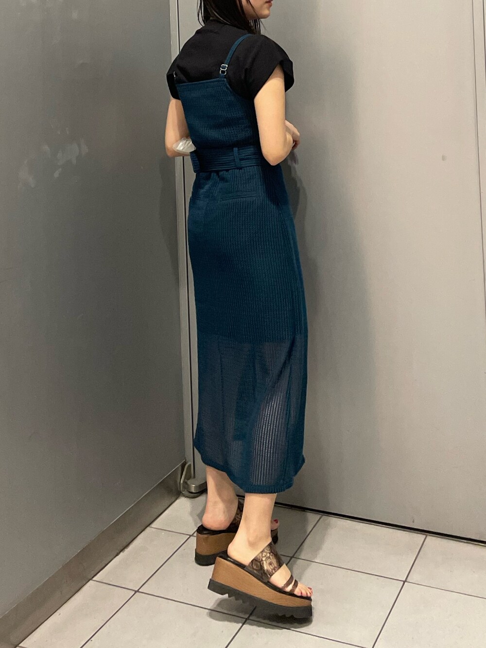 ブルー系のワンピース、ブラック系のTシャツ/カットソー、ブラック系のサンダルを着用したレディースの春コーディネートの2枚目の写真