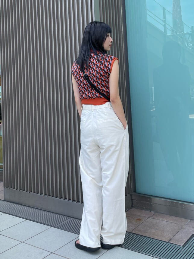 ブラック系のショルダーバッグ、オレンジ系のニット/セーターを着用したレディースの夏コーディネートの4枚目の写真