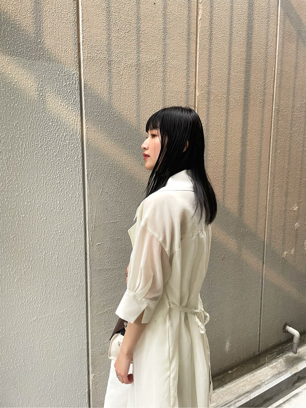 ホワイト系のニット/セーター、ホワイト系のサンダル、ブラウン系のハンドバッグを着用したレディースの春コーディネートの3枚目の写真