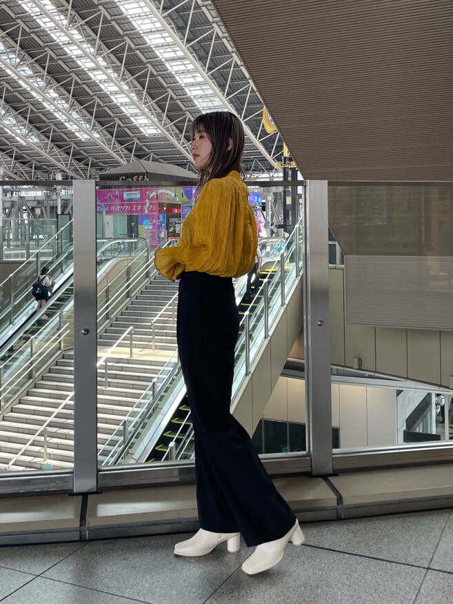 イエロー系のシャツ/ブラウス、ホワイト系のブーツ、ブラック系のスラックスを着用したレディースの夏コーディネートの3枚目の写真