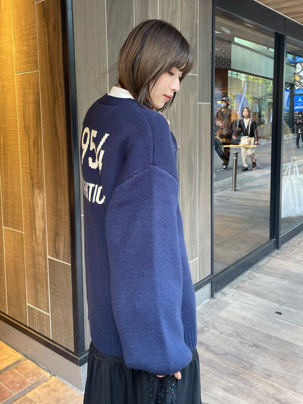 ブルー系のニット/セーター、ブラック系のスカート、ブラック系のブーツを着用したレディースの秋コーディネートの5枚目の写真