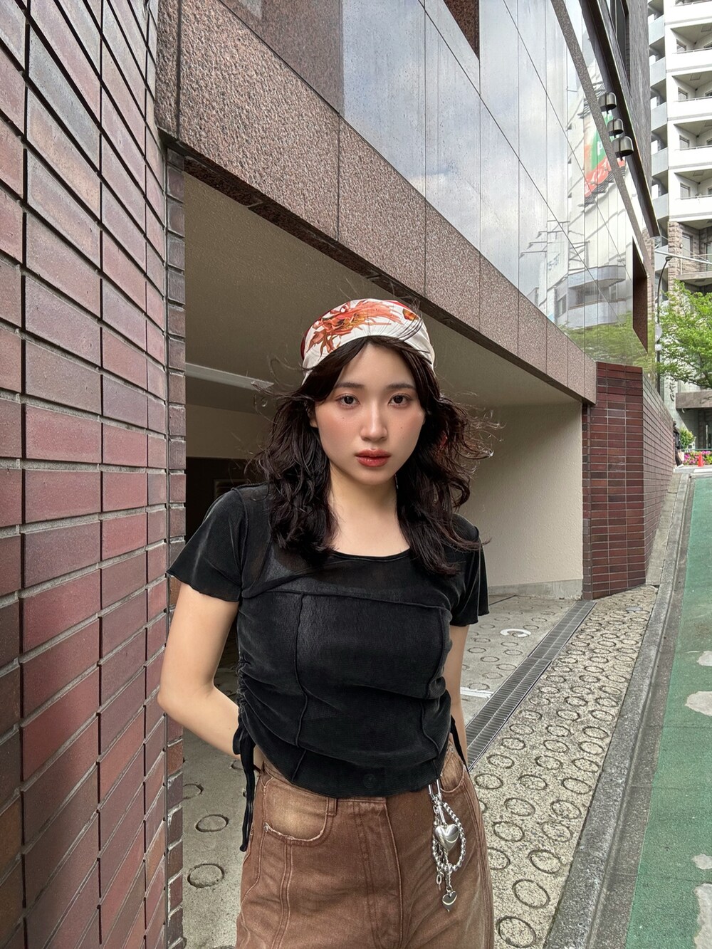 ブラウン系のデニムパンツ、ブラック系のサンダル、オレンジ系のバンダナ/スカーフを着用したレディースの春コーディネートの6枚目の写真