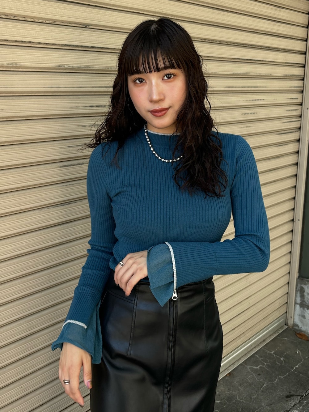 ブルー系のニット/セーター、ブラック系のスカートを着用したレディースの秋コーディネートの3枚目の写真