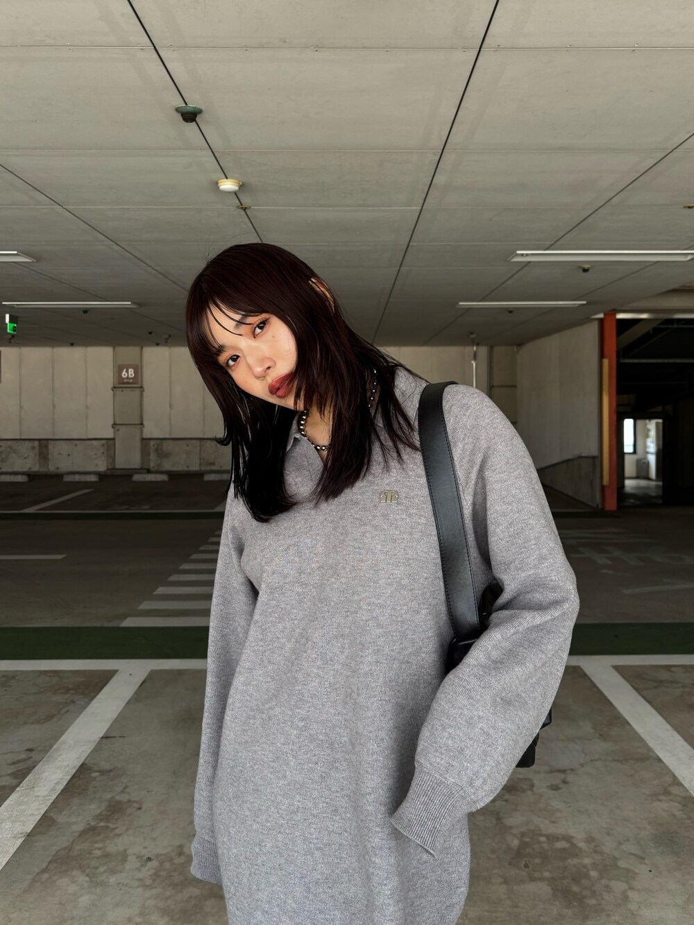 グレー系のワンピース、ブラウン系のブーツ、ブラック系のショルダーバッグを着用したレディースの冬コーディネートの3枚目の写真